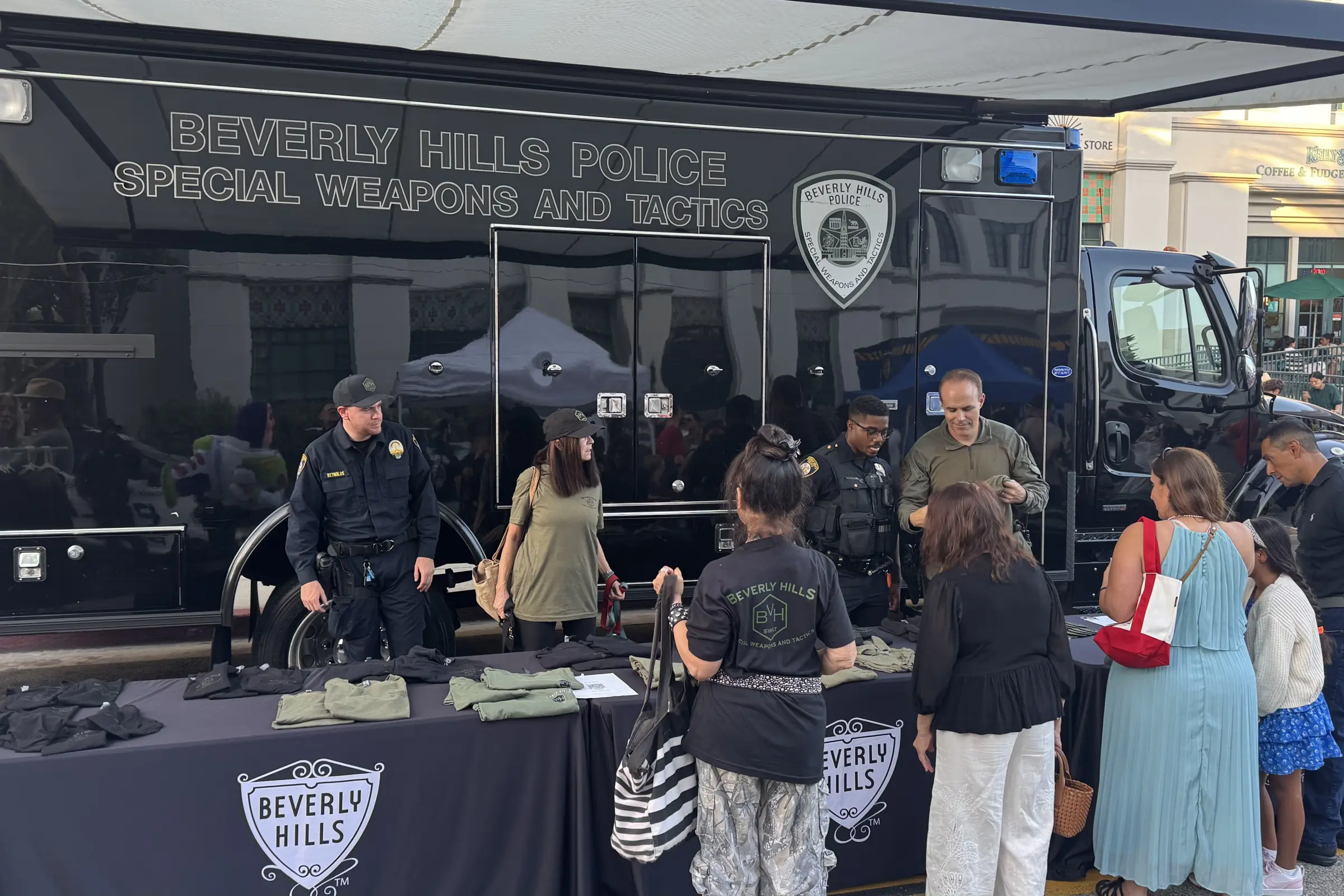 Community members visit the Beverly Hills Police Department display and meet officers stationed beside the Department's SWAT vehicle.