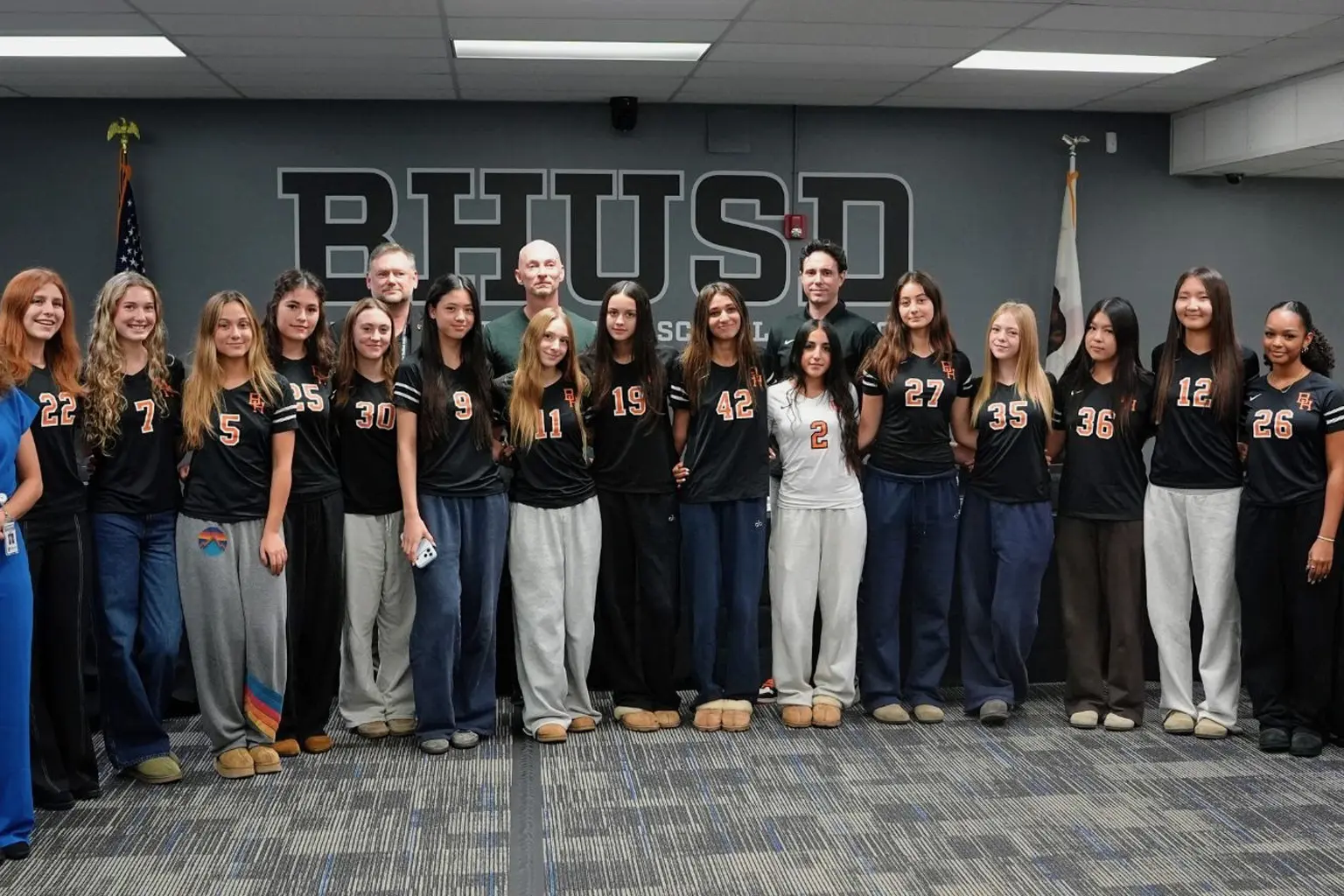 Beverly Hills High School girls volleyball players and adults pose in the BHUSD boardroom.
