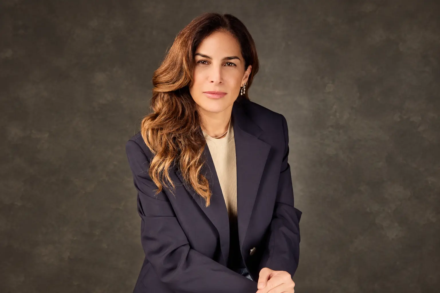 Leslie Gelrubin Benitah wearing a navy blazer against a gray studio background.