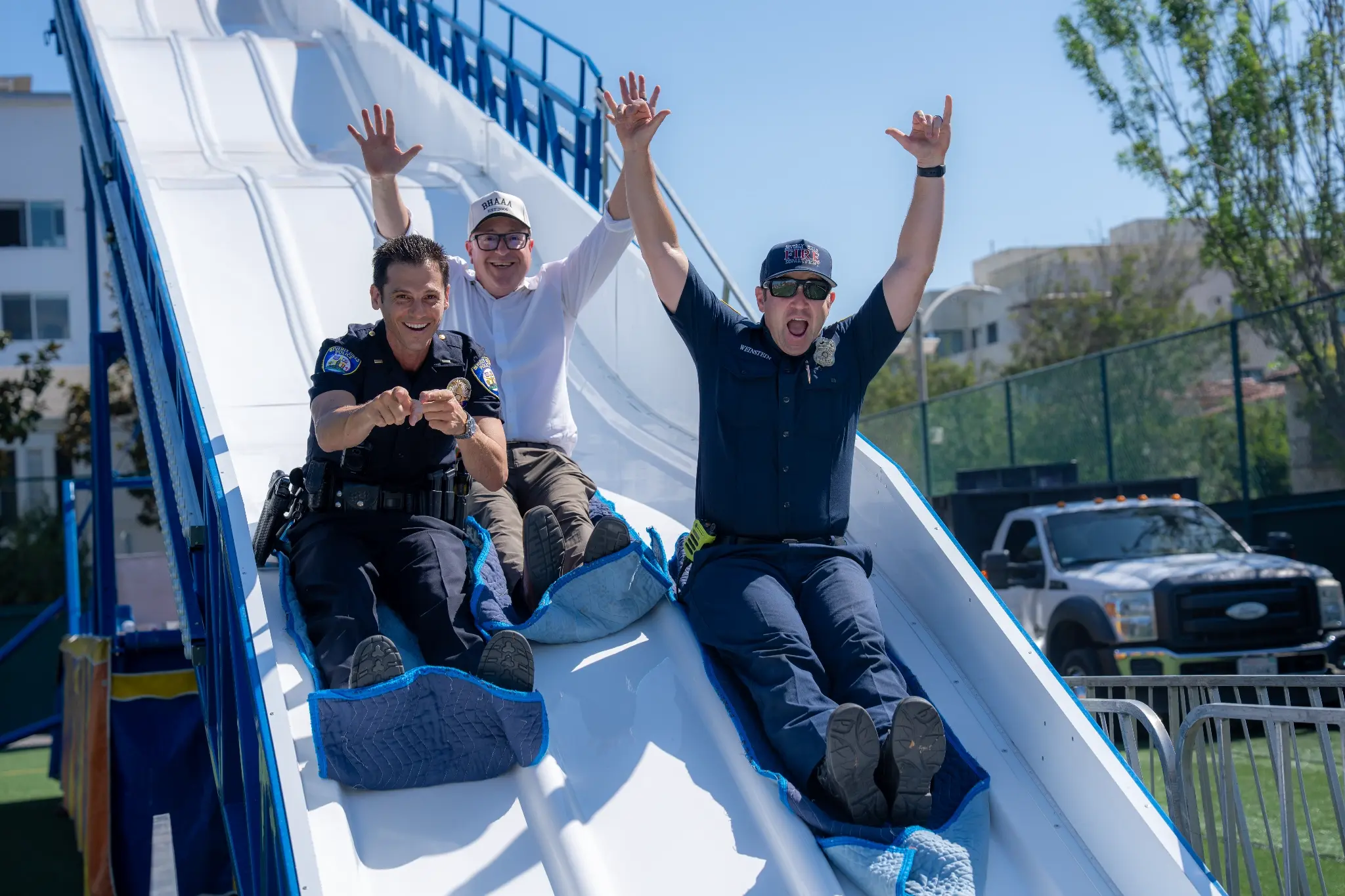 Lt. Billy Fair, Dr. Alex Cherniss, and Firefighter Jimmy Weinstein share a moment of fun at the Beverly Vista Middle School Welcome Back Carnival, reflecting the partnership, joy, and connection that make Beverly Hills so special.