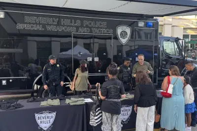 Community members visit the Beverly Hills Police Department display and meet officers stationed beside the Department's SWAT vehicle.